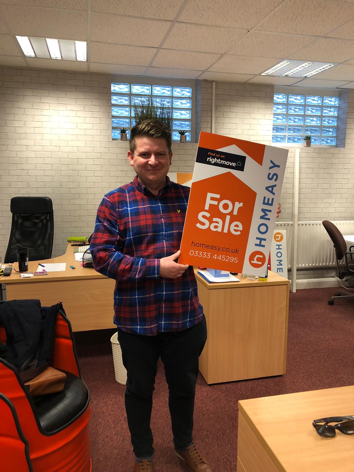 Nathan Pearson with a Homeasy for sale board in the estate agency office