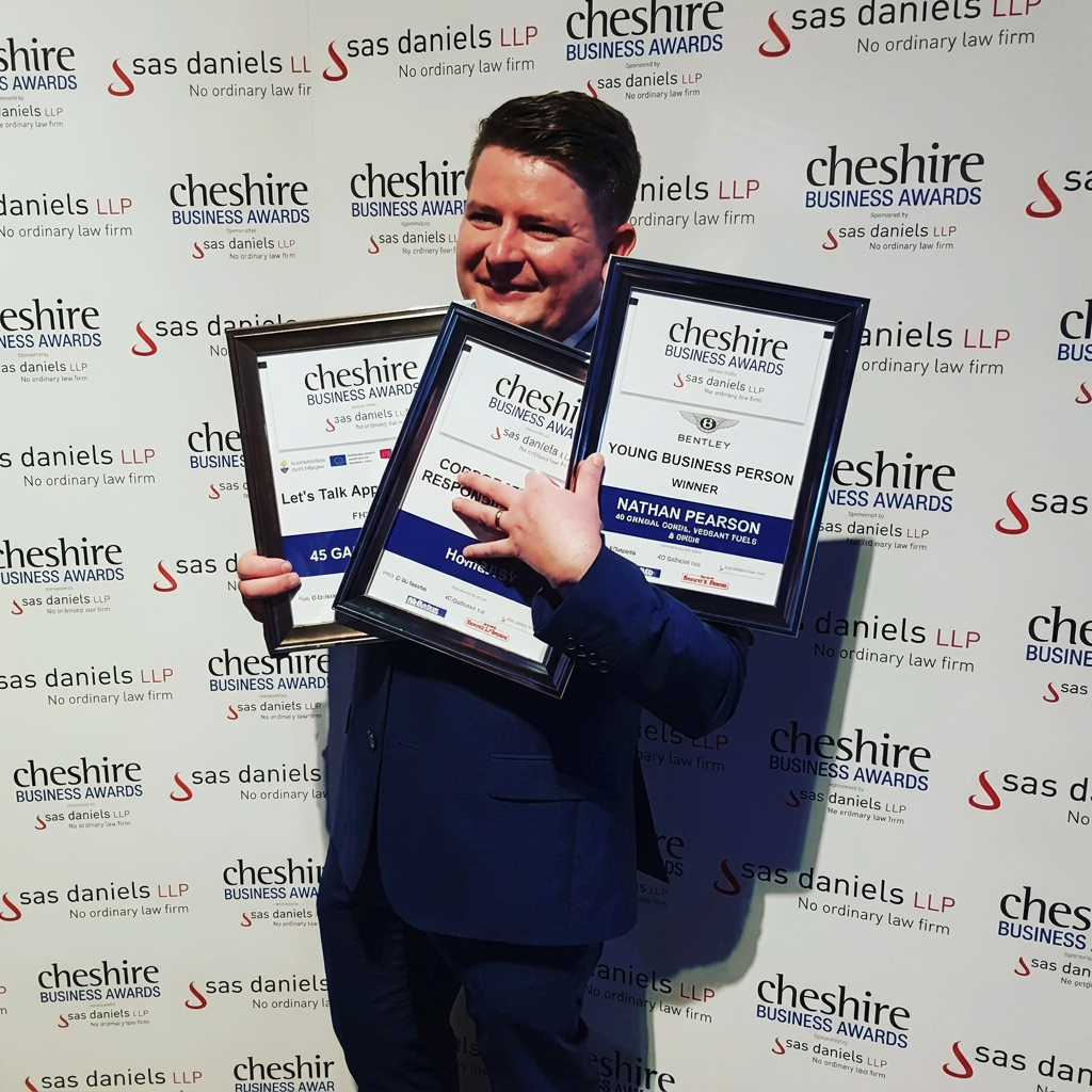 Nathan Pearson holding his Cheshire Business Awards plaques, including Young Business Person of the Year